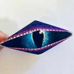 someone is holding a paper origami piece with an image of a blue eye