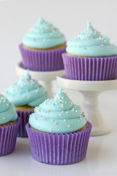 cupcakes with blue frosting and sprinkles on them sitting in front of a cake stand