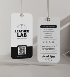 two white tags with black and white designs hang from hooks on a gray background, one has a q - tag attached to it