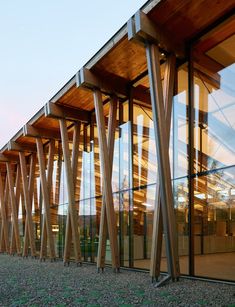 a building that has some very tall wooden poles in front of it and glass windows on the side