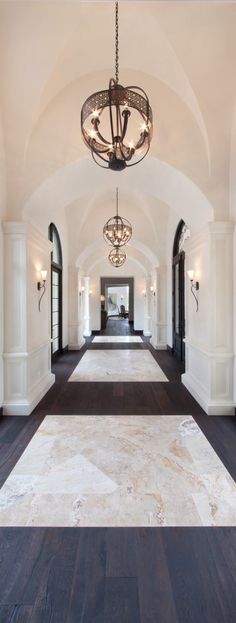 a large hallway with wood floors and chandelier hanging from it's ceiling