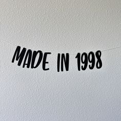 a black made in 1989 sign hanging from a string on a white wall with the words made in 1989 written across it