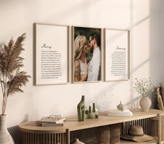 two framed photos hanging on the wall next to a table with vases and flowers