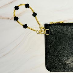 a black purse with a chain attached to it on a white table top next to a cell phone