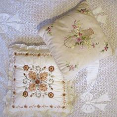 two pillows on a bed next to each other with embroidered flowers and birds in the background