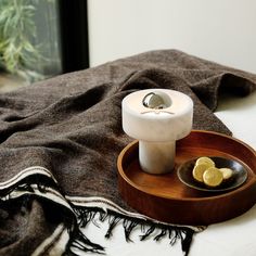 a wooden tray with two lemons and a candle on it next to a window