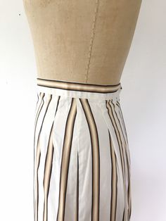 1950s straight pencil skirt creamy white with stripes in four varying shades of brown and a black pinstripe back metal zipper and single button closure single pleats at the hips back walking pleat Excellent vintage condition Approx size Small Measures waist- 25/26 inches hips- 39 inches length- 25 inches Era 50s label- n/a most likely handmade yet unworn Pleated Striped Skirt For Work, Striped Pleated Skirt For Work, Striped Pleated Knee-length Skirt, Midcentury Print, 1950s Skirt, Striped Pencil Skirt, Flower Blouse, Vintage Swimsuit, Vintage Swimsuits