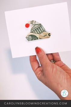 a person holding up a piece of paper with scissors on it and money sticking out of it