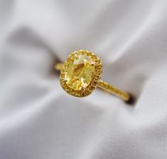 a yellow diamond ring sitting on top of a white cloth