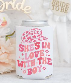 a pink and white can cooler with the words she's in love with the boy on it