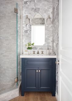 a white and blue bathroom with marble walls, wood flooring and a large mirror above the sink