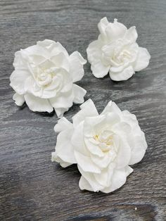 three white flowers sitting on top of a wooden table