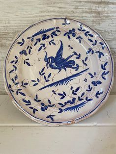 a blue and white plate sitting on top of a wooden table next to a wall