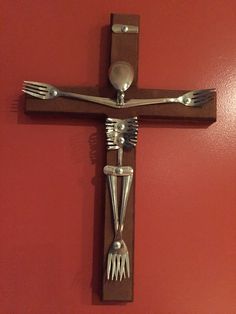 a wooden cross with forks and spoons on it