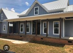 a blue house with white trim on the front and side windows, covered in metal roofing