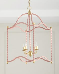 a pink and gold chandelier hanging from the ceiling in a room with white walls