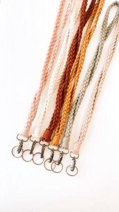 several different colored cords are lined up on a white surface, with metal hooks attached to them