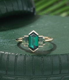 an emerald colored ring sitting on top of a green surface