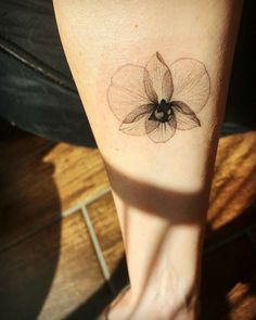 a woman's foot with a small flower tattoo on the left side of her leg