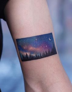 a person with a tattoo on their arm that has the sky and stars painted on it