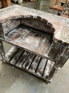 an old wooden table with carvings on the top and bottom, sitting in a warehouse