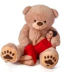 a woman sitting next to a giant teddy bear