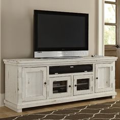 a flat screen tv sitting on top of a white entertainment center in a living room