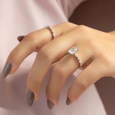 a woman's hand with two rings on her fingers and one ring in the middle