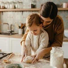 a woman and child are making bread in the kitchen