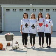 three women in matching shirts stand next to a wheelbarrow with cards on it