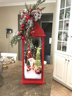 a red lantern with christmas decorations on it in the middle of a kitchen counter top