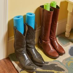 three pairs of cowboy boots are lined up against the wall with blue and green toilet paper