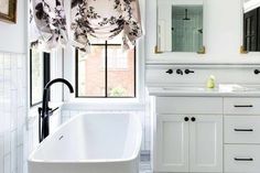 a bathtub in a white bathroom with black and white accessories on the window sill