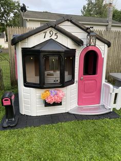 a pink and white dog house sitting on top of a lush green field