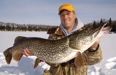 a man holding a large fish in the snow