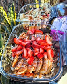 there are many different types of food in the plastic trays on the table, including bananas and strawberries