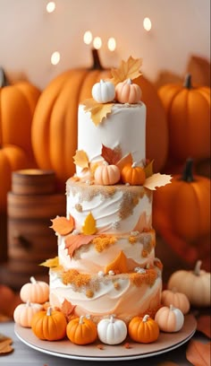 a three tiered cake with white frosting and orange pumpkins on the side