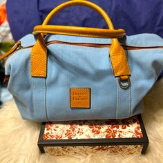 Dooney & Bourke Canvas Duffle/ Boston Style Bag With Leather Handles And Trimmings In A Gorgeous Light Blue. Proceeds Benefit Local Homeless Community. Thank You For Helping Feed Our Nation. Blue Canvas Satchel With Top Carry Handle, Travel Light Blue Satchel, Vintage Blue Bag With Leather Handles, Vintage Blue Bags With Leather Handles, Light Blue Satchel With Removable Pouch For Travel, Light Blue Travel Satchel With Removable Pouch, Light Blue Travel Bags With Leather Handles, Light Blue Double Handle Satchel For Travel, Boston Style