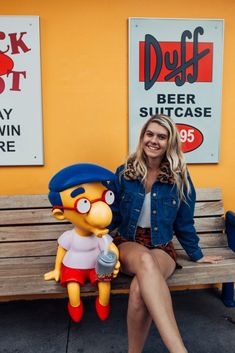 a woman sitting on a bench next to a cartoon character