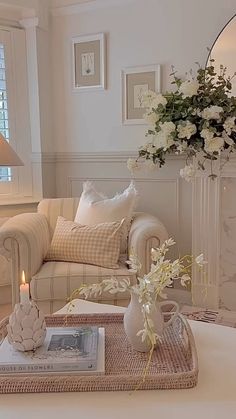 a living room filled with furniture and flowers on top of a table in front of a mirror