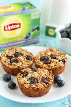 three blueberry oatmeal muffins on a plate next to a carton of milk