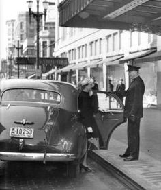 an old black and white photo of people getting into a car at a gas station