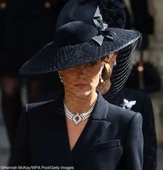 the woman is wearing a black hat with pearls on it