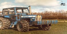 an old blue tractor is parked in the grass