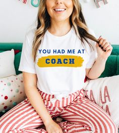 This "You Had Me At Coach" design is the perfect, fun Ted Lasso shirt for anyone that loves sports and Ted Lasso! Sporty T-shirt With Text Print For Sports Events, Athleisure Graphic Print T-shirt For Game Day, Team-colored Crew Neck T-shirt For Cheerleading, Sporty Team Name T-shirt For Workout, Sports Fan Apparel T-shirt With Text Print, Sports Slogan T-shirt Crew Neck, Crew Neck Slogan T-shirt For Sports, Sublimation Print Tops For Game Day Sports Season, Sublimation Print Tops For Game Day