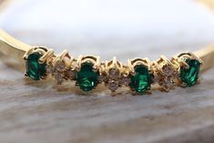 "Vivid genuine diamond and synthetic emerald gold hinged bangle bracelet. This beautiful bracelet includes four 1/2 carat emeralds and 12 round brilliant cut genuine diamonds in 3 clusters. The bracelet is 14 karat yellow gold, is hinged and has a good working clasp. It is from my Mom's personal collection and is in excellent, used condition. The Emerald is great May birthdays, celebrating 20th and 35th wedding anniversaries, or any special occasion. Gemstones Genuine Diamonds Qty & cut: 12 Fine Jewelry With Prong Setting For May Birthstone, Elegant Jewelry With Round Cut May Birthstone, Classic Emerald Bracelets For Formal Occasions, Elegant Emerald Diamond Bracelet For Formal Occasions, Fine Jewelry With Brilliant Cut May Birthstone, Exquisite May Birthstone Jewelry With Prong Setting, Elegant May Birthstone Jewelry With Round Cut, Fine Jewelry With Diamond Accents For May Birthstone, Fine Jewelry For Formal Occasion With May Birthstone