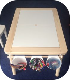 a child's wooden table with two buckets on the bottom and several pencils under it