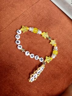 a yellow and white beaded bracelet with the word hello written on it, sitting next to a computer keyboard