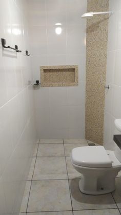 a white toilet sitting inside of a bathroom next to a sink and shower head mounted on a wall