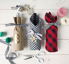 three wrapped gift bags sitting on top of a white wooden floor next to scissors and twine